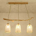 Lodge style wood pendant light featuring natural wood branch and three woven rattan shades for dining room