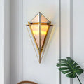 Gold-toned minimalist smoke gray diamond wall light with triangular glass panels and warm glowing light for living room