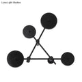 Minimalist black geometric wall light fixture with five circular lights arranged in a triangular pattern for living room