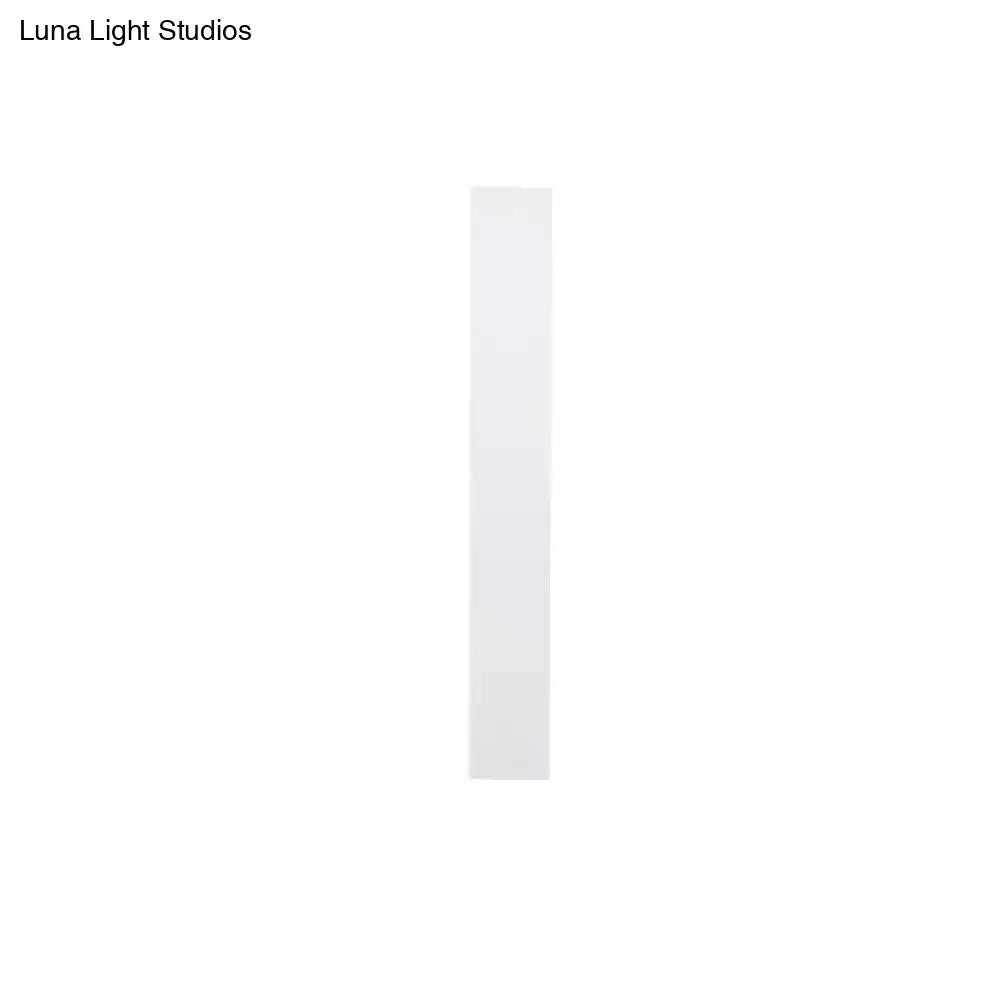 A sleek minimalist white rectangular strip of adhesive tape for direct wired aluminum shade sconce bedroom use