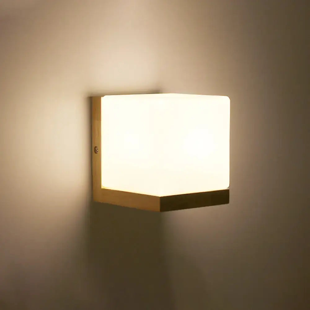 Minimalist brass and glass geometric wall sconce with warm diffused glow and sleek wooden frame for bedroom lighting