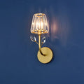 Minimalist gold-toned brass finish wall sconce with faceted crystal shade and two clear dangling crystals wall light