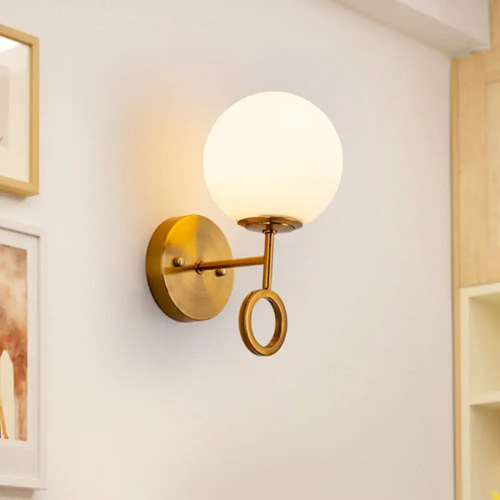 Minimalist brass wall sconce with cream glass shade bedroom light