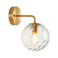Minimalist gold ball sconce with hammered glass shade and brass hardware featuring a textured clear globe