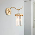 Minimalist gold wall mount light featuring a curved arm and vertical crystal prisms for bedroom decor