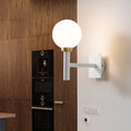 Minimalist white and brass wall lamp with spherical opal glass shade and brass accents for bedroom lighting