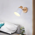Minimalist white metal barrel wall lamp with a conical shade and natural wood accents as a living room wall lamp sconce