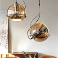 Two modern pendant lights with spherical amber glass pendant shades and chrome metal frames for kitchen use