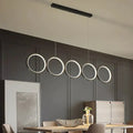 Modern black metal pendant light features five illuminated circular LED rings in a row for hanging island light use