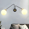 Modern black and brass wall lamp with double arms and frosted milk glass globe shades for bedroom sconce lighting