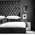Modern black glass and metal semi oval wall light with black finish mounted above a black tufted leather headboard with diamond pattern stitching