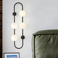 Modern black metal wall sconce with four white glass globe lights in a curved globe wall sconce design for bedroom