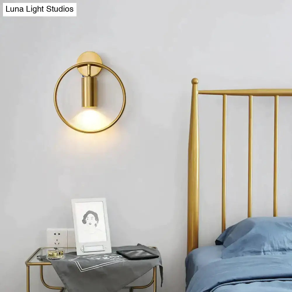 Modern black and gold irwin wall lamp with a gold-toned circular sconce and cylindrical light fixture for bedroom use
