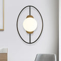 Modern oval wall lamp with black and gold metal halo ring frame and white glass globe for bedroom lighting