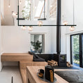 Black ceramic kettle with wooden handle on gray tray under modern black linear island pendant with glass shade in dining room