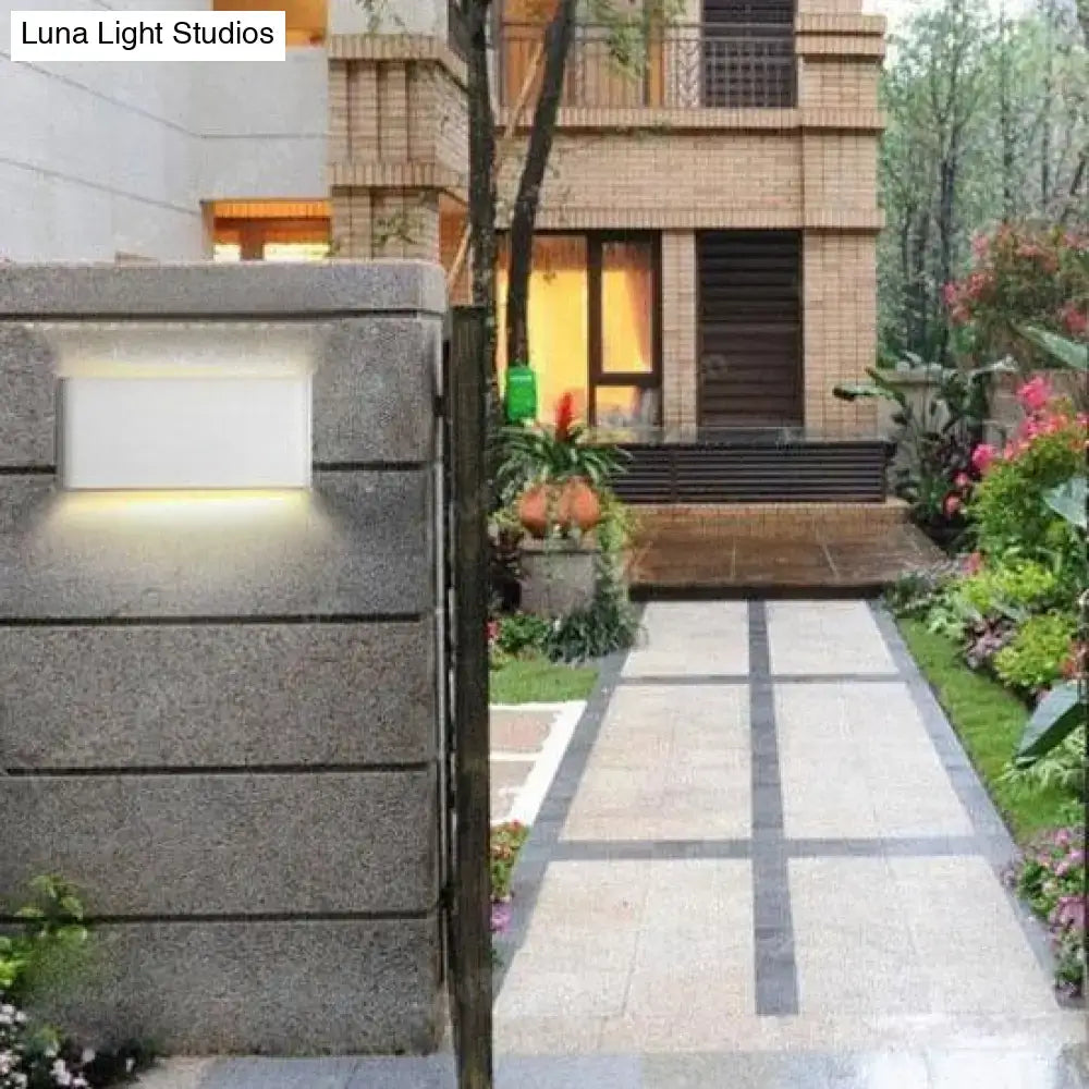 Modern black luna outdoor wall light with sleek white panel and warm led glow mounted on textured gray stone pillar