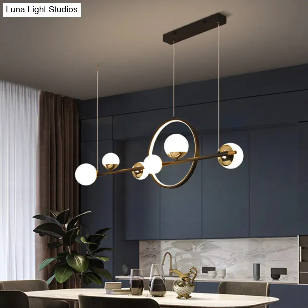 Modern black metal pendant light with brass finish spherical glass globes and central circular ring for dining room
