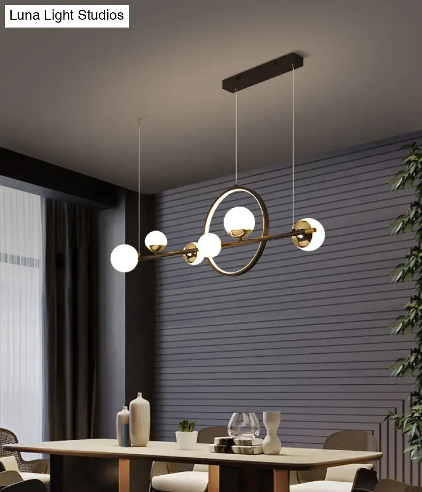Modern black metal pendant light with brass finish spherical glass globes and central circular ring for dining room