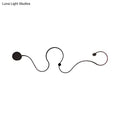 Modern black minimalist wall lamp with sleek curved lines and spherical accents emitting white light for living room use