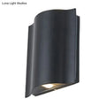 Modern black curved wall light with wavy metal shade and warm white light designed for patio use