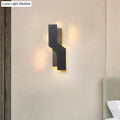 Modern black and clear acrylic wall mount light with angular design emitting warm ambient light for bedroom use