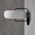 Modern black and white gathered fabric pumpkin wall sconce with white ribbed glass lamp and sleek black metal frame