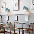 Modern blue metallic bell wall sconce with light blue bell shape and perforated lower section for restaurant lighting