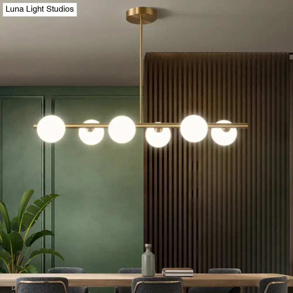 Modern brass pendant light with five frosted spherical glass shades for dining room illumination