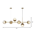 Modern brass-toned 6-light linear dining room pendant with smoke gray glass ball shades by DecorBites™