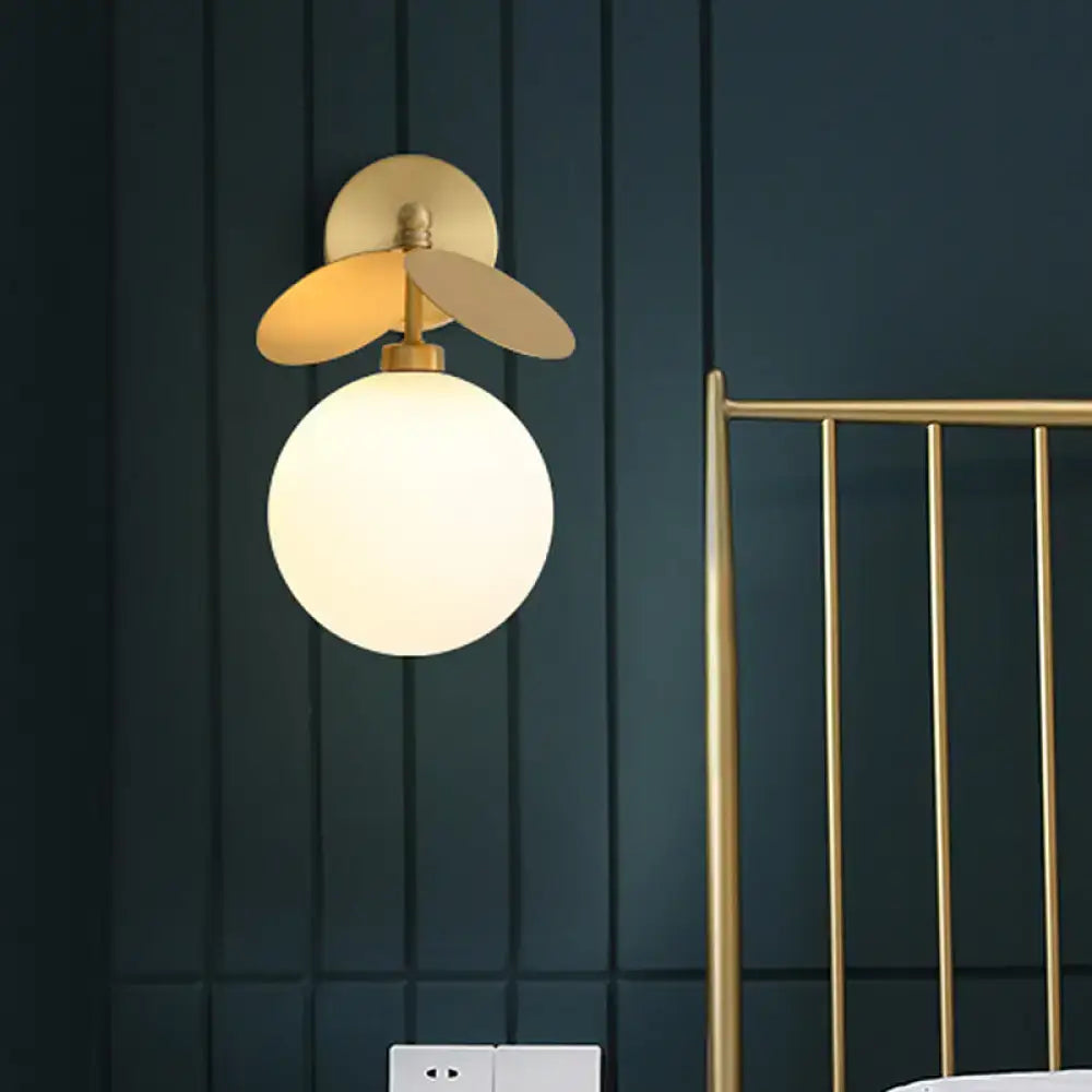 Modern brass leaf wall lamp with cream glass bedroom sconce