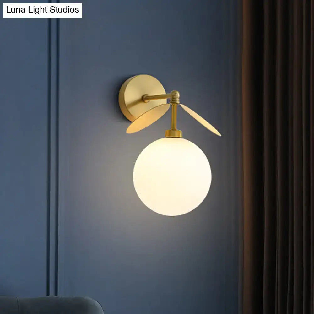 Modern brass leaf wall lamp with cream glass bedroom sconce