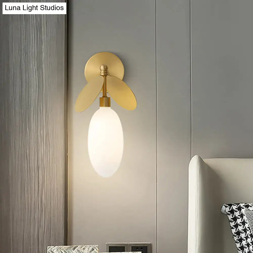 Modern brass leaf wall lamp with cream glass bedroom sconce