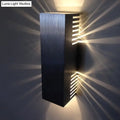 Modern brushed silver wall light with vertical slats emitting warm white light for bedroom sconce lighting