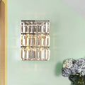 Modern chrome clear crystal wall lamp with three rows of faceted prisms in a sleek rectangular bedroom sconce