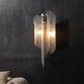 Modern chrome crystal wall sconce with curved frame and clear cascading beads for bedroom bedside lighting