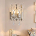 A modern chrome crystal wall sconce light type with polished chrome frame and dangling crystal teardrops for bedroom