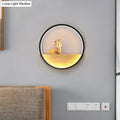 Modern circular black wall light with warm glow illuminating a decorative deer figurine on a wooden living room shelf