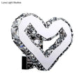 A modern clear crystal heart wall lamp with faceted crystal accents on a chrome base emitting warm white light