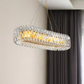 Modern gold and clear crystal oval pendant light with faceted crystal elements for dining room illumination
