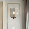 Elegant gold-framed wall sconce with gray glass triangle panels and warm glowing bulb for bedroom lighting