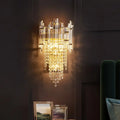 A modern gold clear crystal wall lamp with cascading glass prisms designed as a tiered bedroom wall light