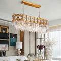 Modern gold-toned rectangular island pendant light with crystal droplets and oval suspension for dining room