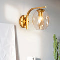 Modern gold curved arm glass wall sconce with clear rounded shade and exposed bulb for bedroom lighting in blue green decor