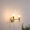 Modern gold double arm wall sconce with two flame-shaped clear glass shades for living room lighting