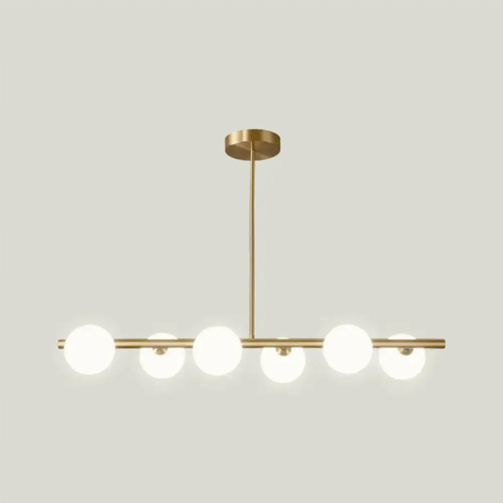 Modern gold island pendant lighting featuring five frosted glass globe shades in a linear island pendant design