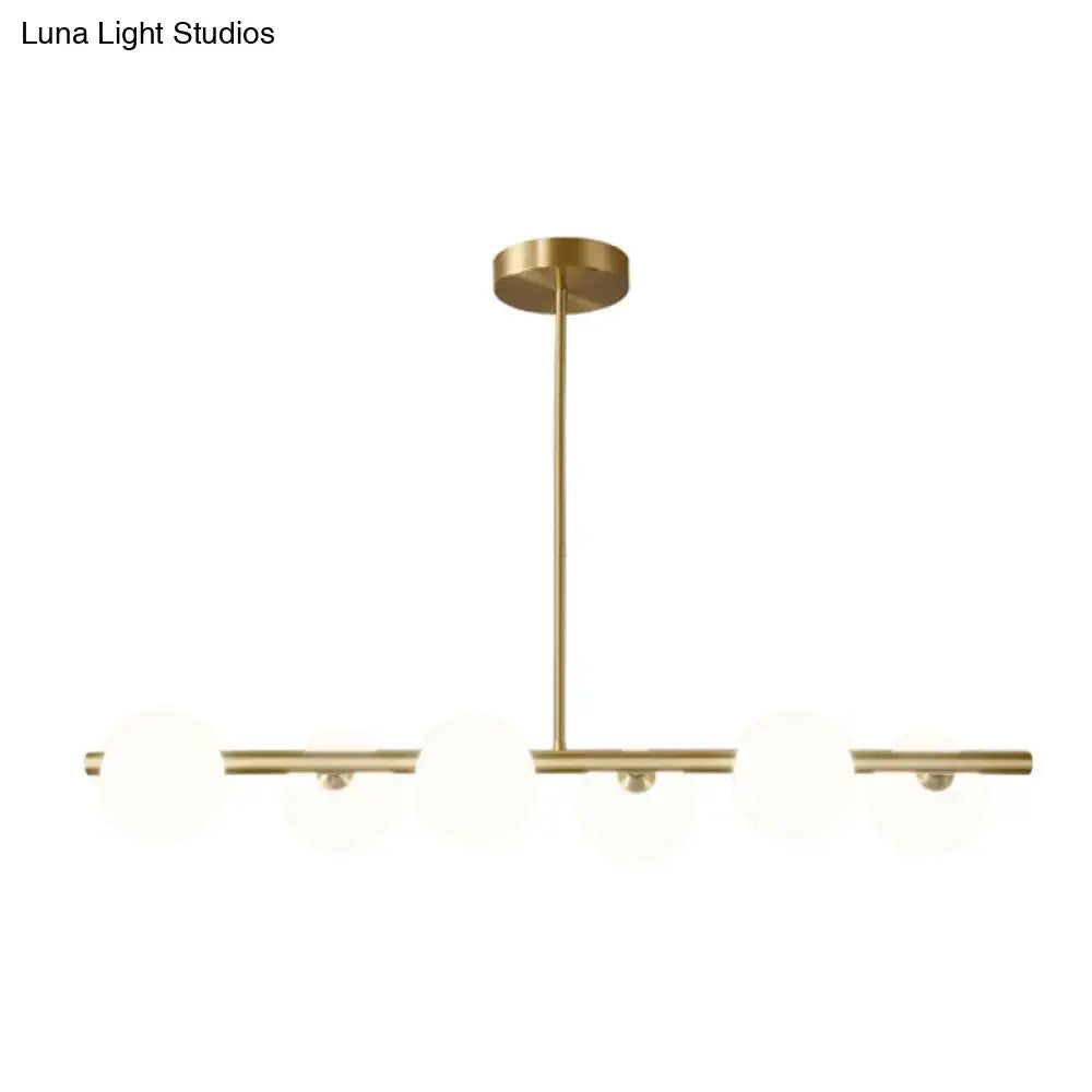 Modern brass island pendant lighting with three frosted glass globe shades and minimalist horizontal bars for dining room
