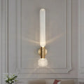 Modern gold ribbed glass wall lighting fixture with translucent cylinder and crystal base on brushed brass backplate