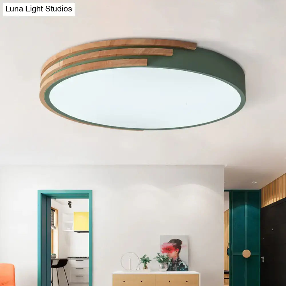 Modern circular flush mount ceiling light with matte green ring and wood slats emitting soft white light 16 inch width