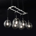 Modern chrome-finished pendant island lighting with five clear glass globe shades and smoke glass accents in nickel bronze