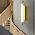 Modern minimalist gold led wall lamp with cylindrical frosted glass diffuser and curved metal frame for bedroom use